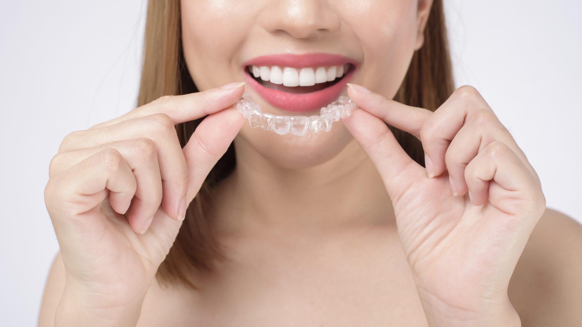 mujer sonriente joven que sostiene apoyos invisalign estudio salud dental concepto ortodoncia